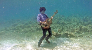 Sasha Mizgulin, lead singer of Egoists playing his guitar underwater in video for Maiden of the Sea